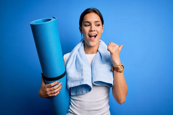 Young Beautiful Brunette Sportswoman Wearing Towel Holding Mat Yoga Pointing - Stock-foto