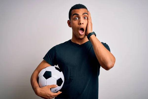 白い背景の上にサッカーボールを保持サッカーをプレイし いくつかのアフリカ系アメリカ人の男は恐れてショックを受け 驚きと驚きの表情で手で顔 — ストック写真