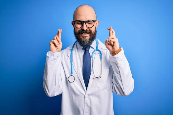 Pohledný Holohlavý Doktor Vousy Brýlemi Stetoskopem Modrém Pozadí Ukazoval Prstem — Stock fotografie
