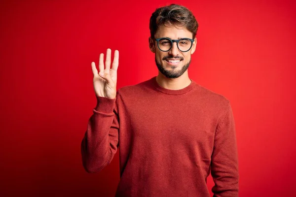 Sakallı Gözlüklü Süveterli Genç Adam Kırmızı Arka Planda Dikiliyor Parmaklarıyla — Stok fotoğraf