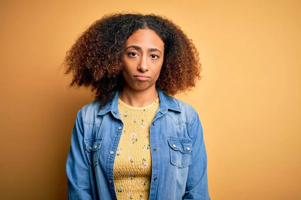 黄色の背景にカジュアルなデニムシャツを着てアフロの髪を持つ若いアフリカ系アメリカ人女性は落ち込んでおり 苦痛のために心配し 怒って恐れて泣いています 悲しい表情 — ストック写真