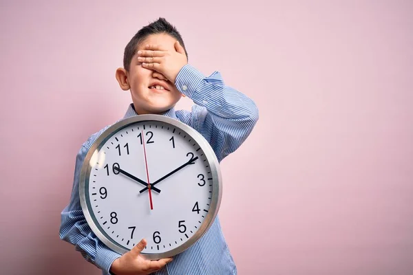 Młody Chłopiec Trzyma Wielki Minutowy Zegar Odosobnionym Różowym Tle Zestresowany — Zdjęcie stockowe