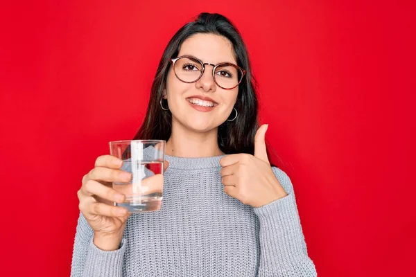 Mladá Krásná Žena Pije Sklenici Čerstvé Vody Přes Izolované Červené — Stock fotografie