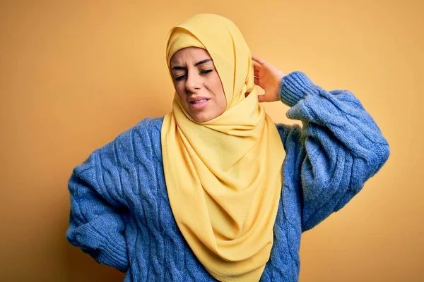 若いです美しいですブルネットムスリム女性身に着けていますArab Hijab上の隔離された黄色の背景上に首の痛みの負傷 手で首に触れます 筋肉痛 — ストック写真