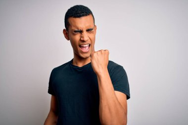 Beyaz arka planda dikilen gündelik tişörtler giyen genç ve yakışıklı Afro-Amerikan erkeği kolları havada ve gözleri kapalı olarak başarısından dolayı şaşkınlığı ve şaşkınlığı kutluyor. Kazanan konsept.