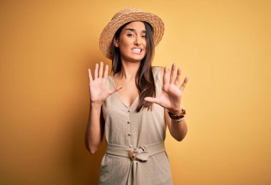 Genç, güzel, esmer kadın tatilde. Sıradan bir elbise giyiyor ve şapkası var. Korkudan ödü patlıyor. Panik konsepti.