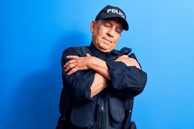 Gri saçlı, polis üniforması giyen, kendine sarılan mutlu ve pozitif, kendinden emin gülümseyen yaşlı adam. Sevgi ve özgüven. 