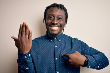 Genç Afrikalı Amerikalı adam, beyaz arka planda parmağında altın evlilik yüzüğü gösteriyor.