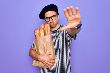 Mavi gözlü genç fırıncı, Fransız beresi takıyor, elinde ekmek çantası var, dur işareti yapıyor, ciddi ve kendinden emin bir ifadeyle, savunma jesti yapıyor.