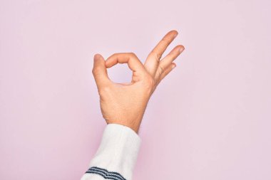 İzole edilmiş pembe arka planda parmaklarını gösteren beyaz bir gencin eli işaret ediyor. Onaylama ifadesi parmaklarıyla sembol yapıyor.