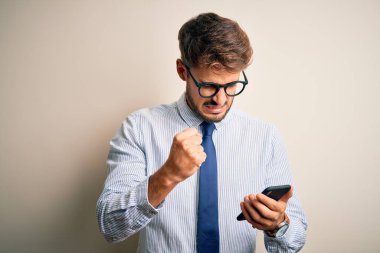 Genç iş adamının beyaz arka plan üzerinden akıllı telefonu kullanması sinirlenmiş ve sinirlenmiş bir şekilde bağırması, çıldırmış ve el kaldırarak bağırması, öfke konsepti.