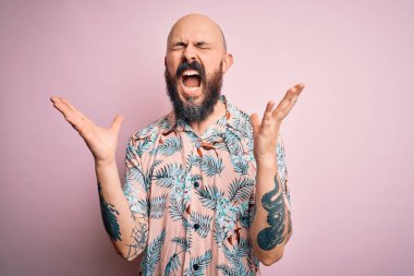 Sakallı ve dövmeli yakışıklı, pembe arka planda sıradan bir çiçek desenli gömlek giyen kolları havada ve gözleri kapalı heyecanlı bir şekilde başarıyı kutlayan kel bir adam. Kazanan konsept