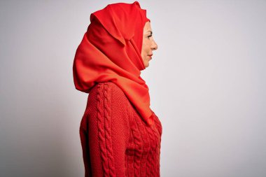 Orta yaşlı esmer kadın, geleneksel tesettüre bürünmüş, yalıtılmış beyaz arka plana bakıyor, rahat profil pozu veriyor, doğal bir yüzü ve kendine güvenen bir gülüşü var..