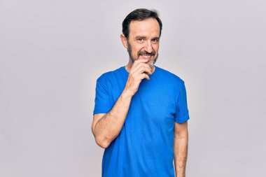 İzole edilmiş beyaz arka plan üzerinde sıradan tişörtler giyen yakışıklı bir adam kameraya kollarını kavuşturmuş ve çenesine dokunmuş bir şekilde gülümsüyor. Olumlu düşünüyorum..