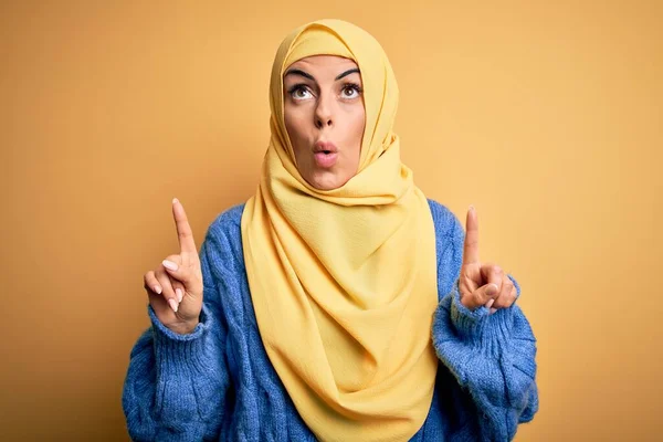 年轻美丽的黑发穆斯林女子头戴阿拉伯头巾 头戴黄褐色头巾 惊讶地抬起头 用手指和胳膊指指着 — 图库照片