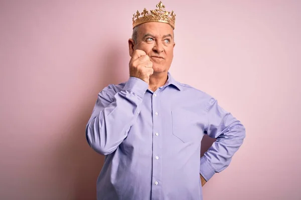 質問について考える顎の手で孤立したピンクの背景の上に立って王の黄金の冠を身に着けている中世のホーリーマン 集中的な表現 思慮深い顔で微笑んだ 疑いの概念 — ストック写真