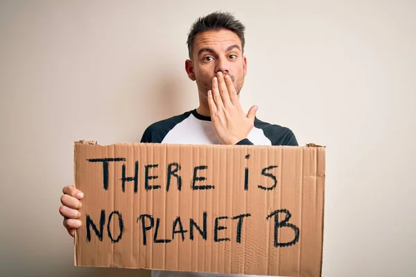 Young handsome man asking for environment holding banner with planet message cover mouth with hand shocked with shame for mistake, expression of fear, scared in silence, secret concept