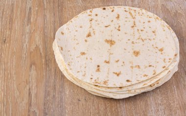 Tahta masa arkasında ev yapımı tam buğday unlu tortilla yığını