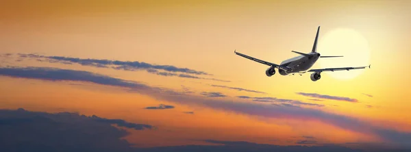 Vliegtuig vliegen boven de wolken in het licht van de zonsondergang — Stockfoto