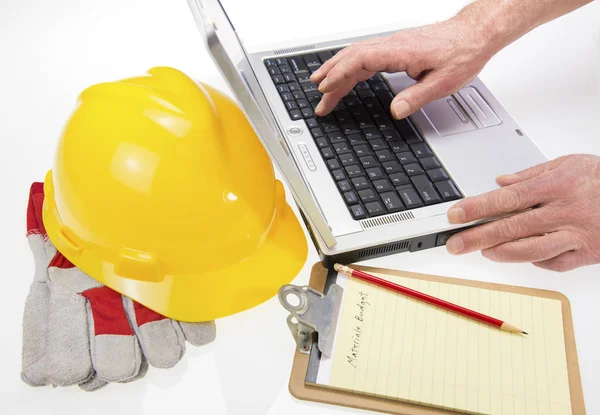 Planes de construcción en el ordenador portátil con Hardhat —  Fotos de Stock