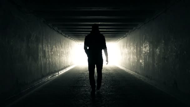 Человек, идущий по тоннелю к свету — стоковое видео