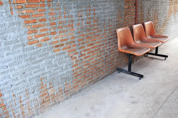 Cadeira laranja em pé no quarto sobre a parede de tijolo laranja — Fotografia de Stock