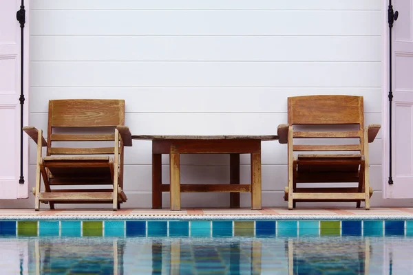 Cadeira de madeira no chão ao lado da piscina — Fotografia de Stock