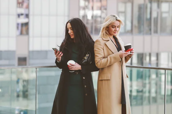 two women walk in the city, drink coffee and enjoy the rest