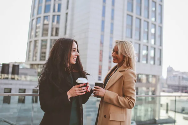 two women walk in the city, drink coffee and enjoy the rest