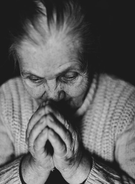 Черно-белый портрет старухи, молящейся
