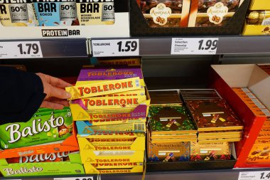 Almanya - Aralık 2019: İsviçre çikolatası markası Toblerone bir dükkanda. Lidl indirimli süpermarkette çeşitli şekerlemeler..