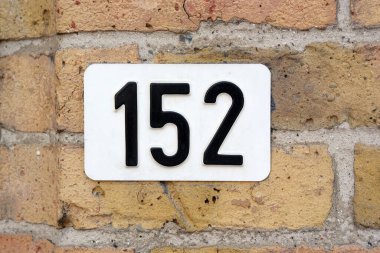 152 numaralı ev tabelası. Beyaz 125 numaralı tabak tuğla bir duvara monte edildi..