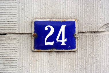 24 numaralı ev tabelası. Mavi emaye kaplı 24 numaralı tabak sıva duvarına monte edilmiş..