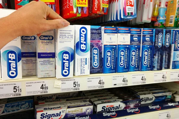 BELGIUM - 2018 AĞUSTOS: Bir dükkanda diş macunu seçmek. Oral-B, Procter & Gamble 'a ait bir ağız hijyeni ürünüdür..