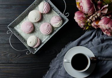 Pembe ve beyaz marshmallow bir vintage tepsi ve buket çiçek karanlık bir arka plan üzerinde