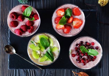 Ürün yelpazesine smoothies kızılcık ahududu çilek kivi karanlık bir arka plan üzerinde