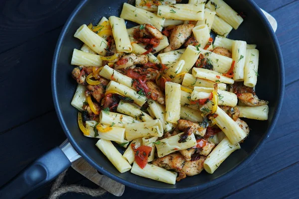 Tortiglione pasta con pollo en una salsa de tomate, pimienta y perejil sobre un fondo de madera oscura —  Fotos de Stock