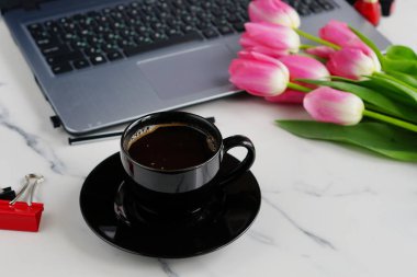 Düz yatıyordu, en iyi görünümü office tablo kadınsı Resepsiyon. dizüstü bilgisayar, fincan kahve ve buket Pembe Lale ile çalışma alanı.