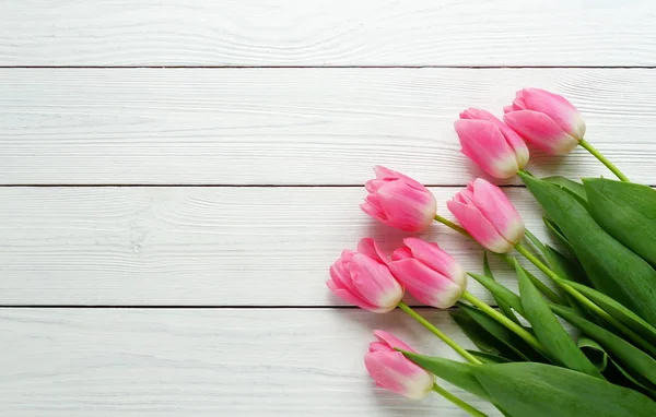 Un ramo de tulipanes rosados sobre un fondo de madera blanco — Foto de Stock
