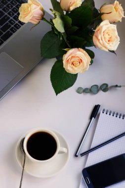 dizüstü bilgisayar, kahve ve gül buketi.