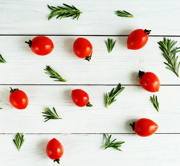 Stillleben mit Kirschtomaten und Rosmarinzweigen auf weißem Holzgrund. flache Lage — Stockfoto