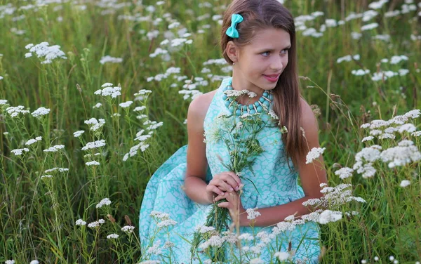 Retrato de una hermosa niña en un vestido azul y adornos posando al aire libre entre flores blancas —  Fotos de Stock