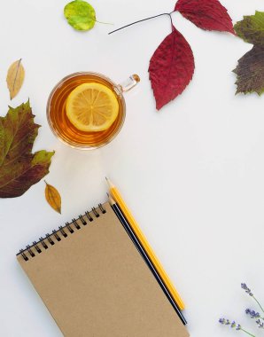 Düz yatıyordu sonbahar kavramı. Fincan çay ve limon, çizimler ve sonbahar yaprakları için not etmek ile. Üstten Görünüm. Kopya alanı