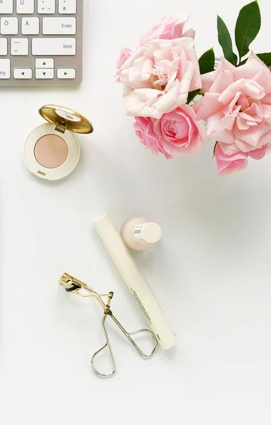 Concept de blog beauté. Accessoires de maquillage féminin et bouquet de roses roses sur fond blanc. Pose plate, vue sur le dessus bureau féminin, espace de travail avec ordinateur portable . — Photo