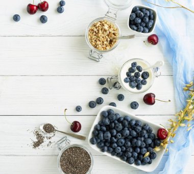 Taze yaban mersini, granül, chia tohumu, Beyaz ahşap zemin üzerinde bir cam kavanoza yaban mersini ile yoğurt lezzetli ve sağlıklı bir kahvaltı. Üstten Görünüm. Kopya alanı