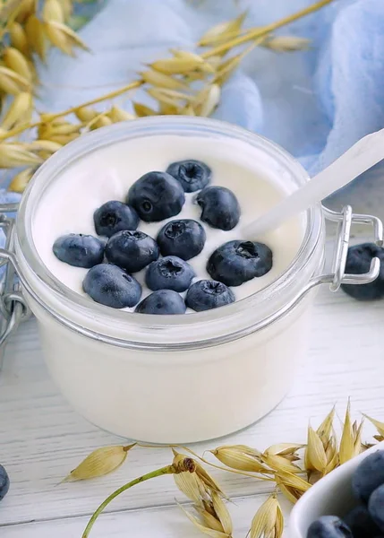 Ein leckeres und gesundes Frühstück mit frischem Joghurt mit Blaubeeren in einem kleinen Glas auf weißem Holzgrund. Nahaufnahme — Stockfoto