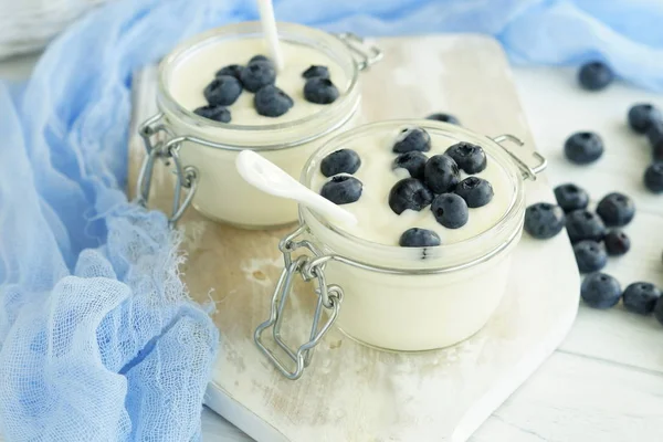 Chutné a zdravé snídaně, čerstvý jogurt s borůvkami v malé skleničky na bílé dřevěné pozadí. — Stock fotografie
