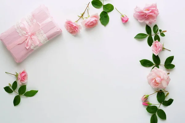 Bouquet of beautiful pink roses and gift in pink packing on white background.Top view.Copy space — Stock Photo, Image