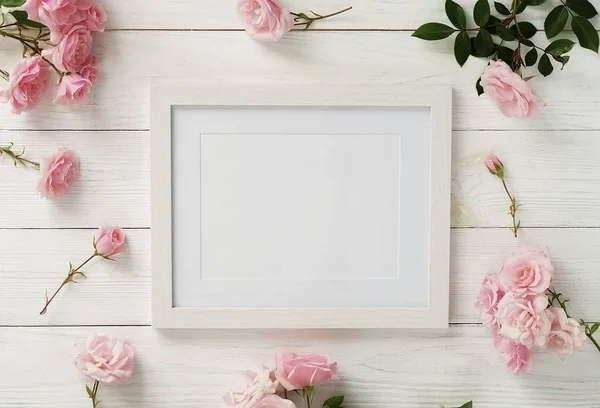 Modèle de cadre d'affiche, vue de dessus, roses roses sur fond en bois blanc.Concept de vacance.Pose plate. Espace de copie — Photo