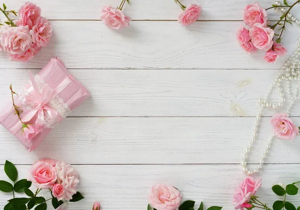 Buquê de belas rosas rosa e presente na embalagem rosa no fundo de madeira branca. Espaço view.Copy superior — Fotografia de Stock